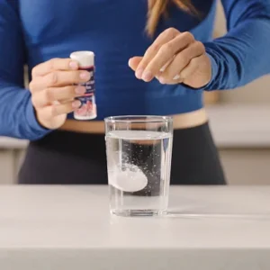 MaxiNutrition Hydration Tabs – Frau bereitet Elektrolyt-Drink im Glas zu