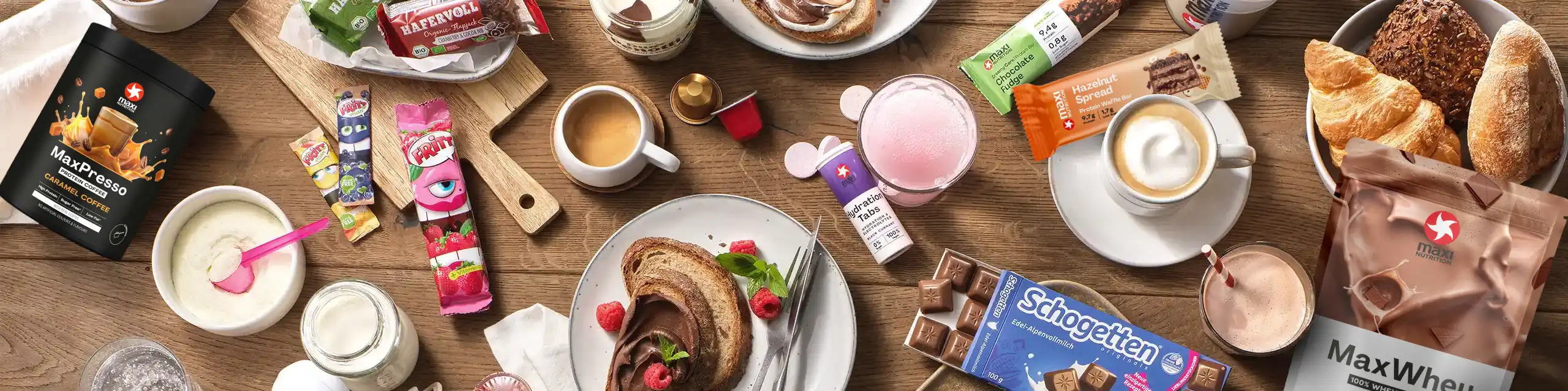 Draufsicht auf verschiedene Krüger-Markenprodukte – Schokolade, Kaffee, Snacks, Croissants und Getränke auf Holztisch
