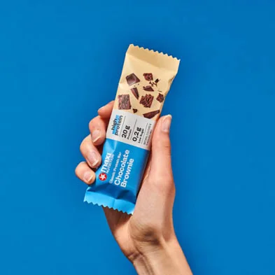 MaxiNutrition Classic Protein Bar Chocolate Brownie 40g – Riegel in der Hand vor blauem Hintergrund